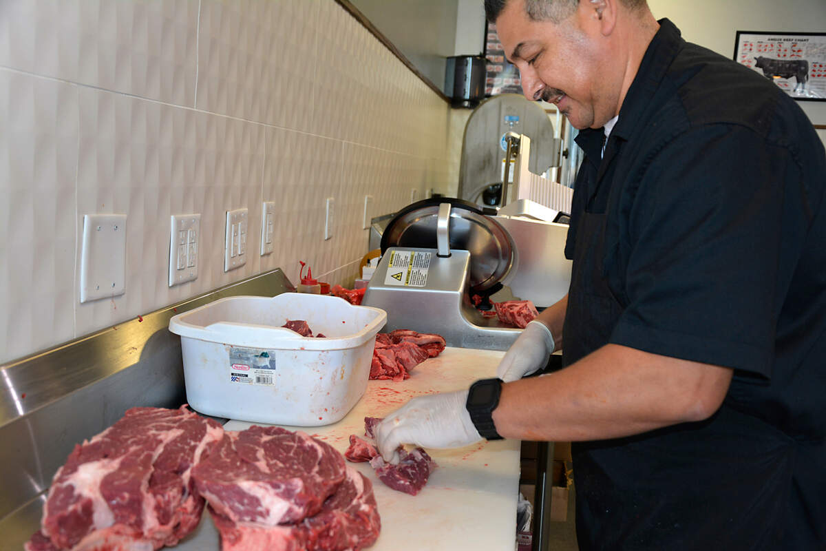 Co-owner Carlos Virgen cuts beef in his new store, Chuck’s Butcher Shop.