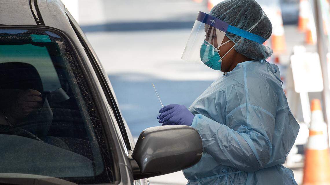 Registered nurse Brenda Williams collects a nasal sample from a client at the drive-up COVID-19 test site in Salida, Calif., on Tuesday, Nov. 10, 2020.