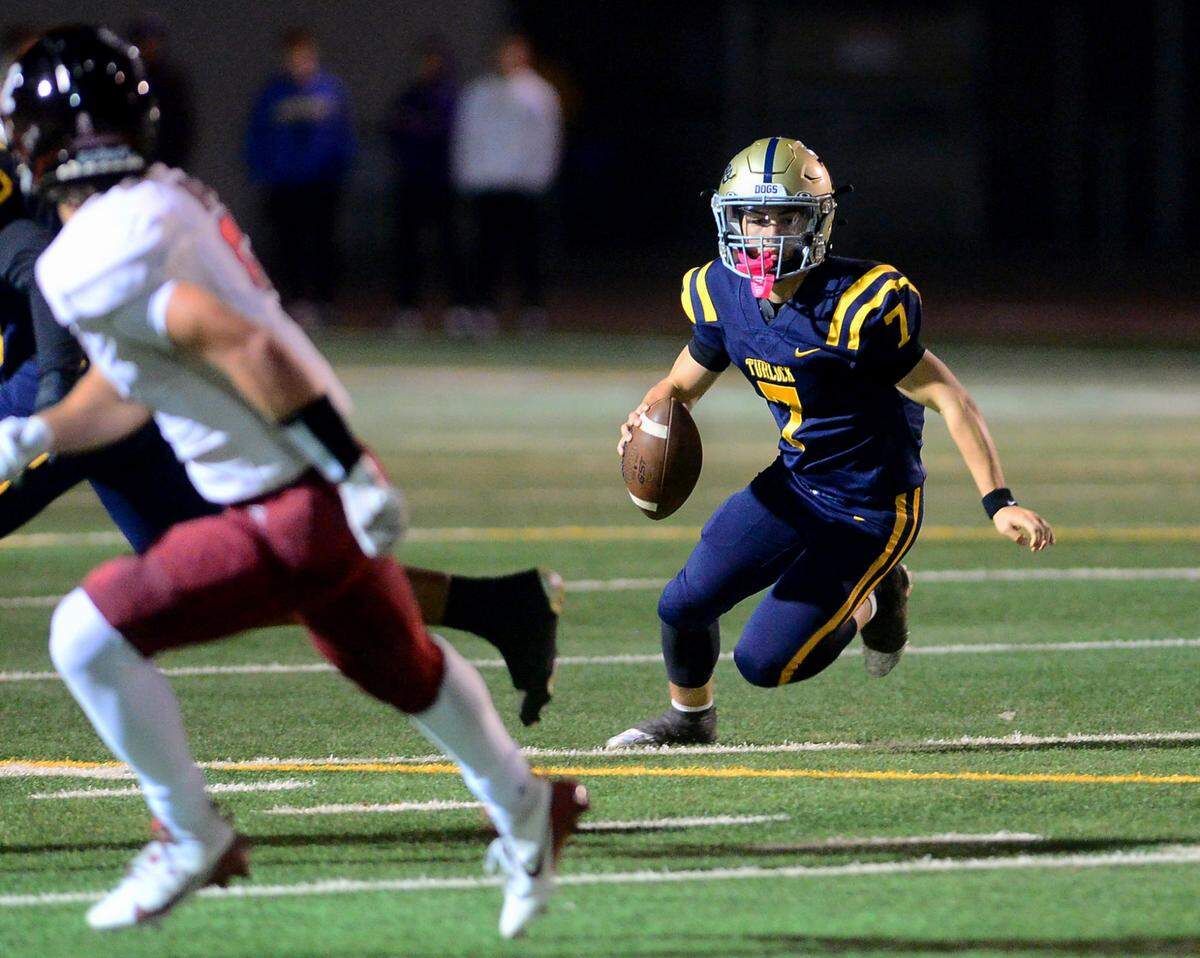 Turlock quarterback Scout Silva (7) scrambles out of the pocket during a Division 1 CIF San-Joaquin Section playoff game between Turlock High School and Laguna Creek High School at Turlock High School in Turlock California on November 8, 2024. Turlock won the game 48-12.