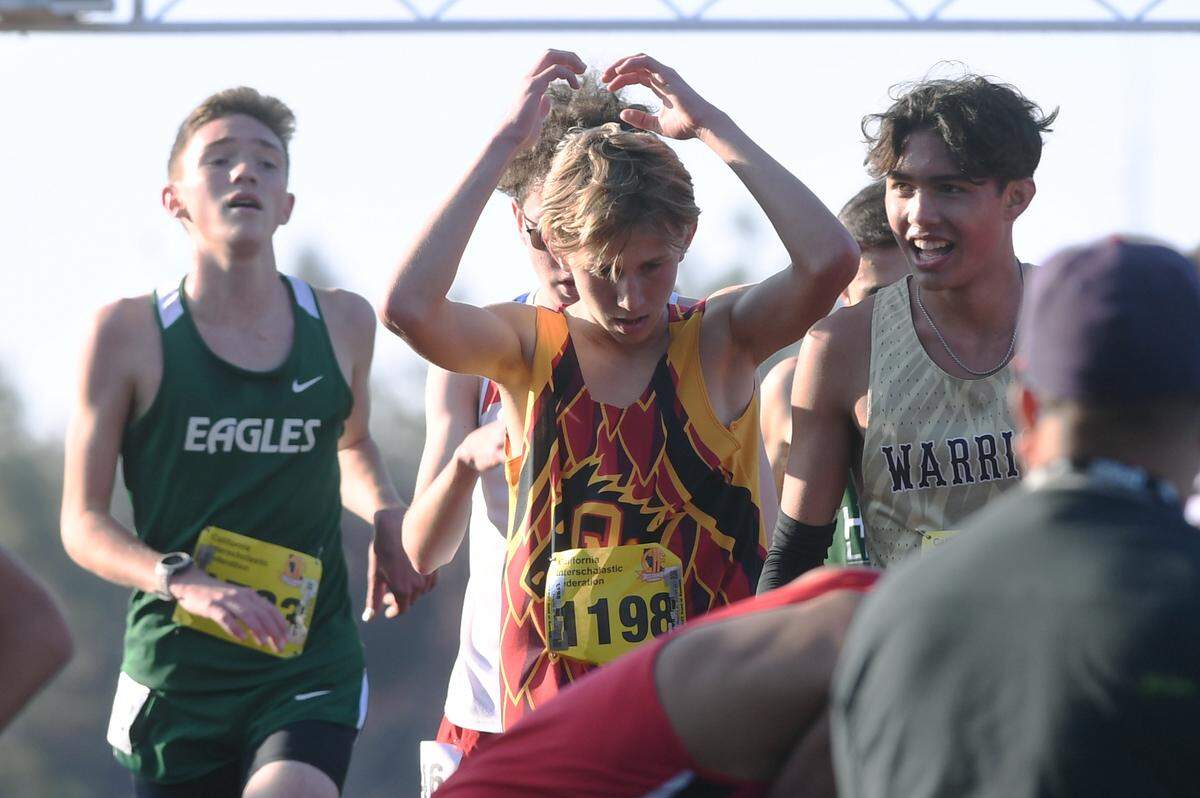 Oakdale’s Caleb Cavanaugh, center, seen after crossing the finish line in the Boys Division III race at the CIF state cross country championships held at Woodward Park Saturday, Nov. 27, 2021 in Fresno.