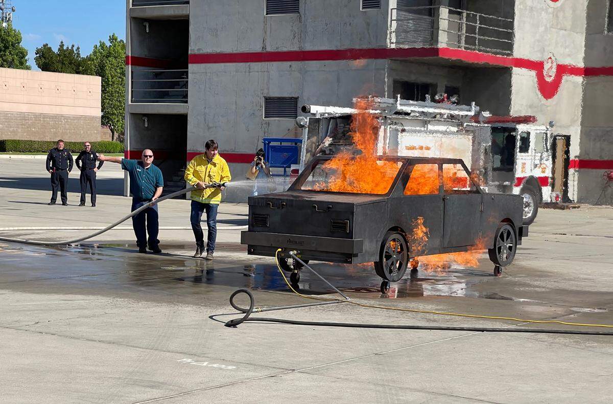 Congressman Josh Harder helped put water on a car fire prop during a visit in 2021.