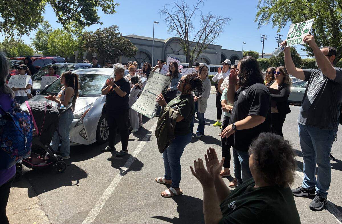 People holding signs in support of MediCaid point them towards 2010 15th St. 