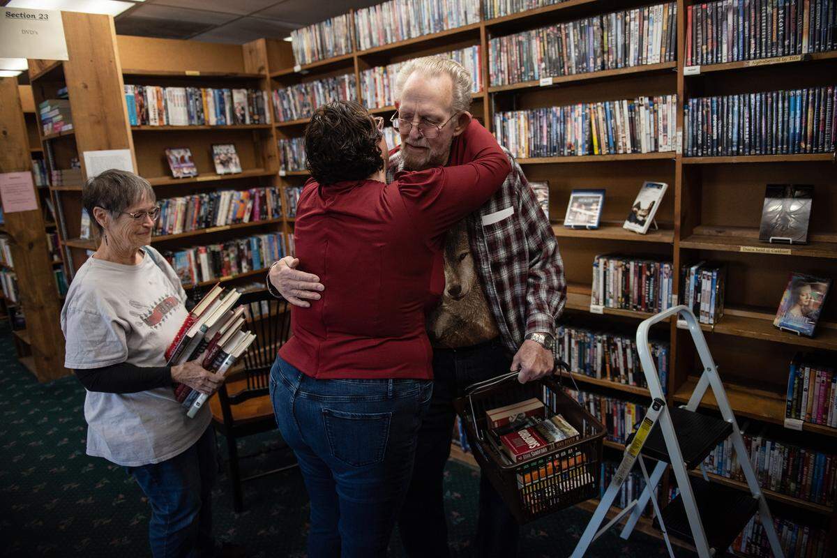 Longtime customer Don Arney gives owner Paula Kiss a hug at Yesterday’s Books in Modesto, Calif., Thursday, Oct. 27, 2022. Barbara Arney, left, picked up a stack of cookbooks during one of her last visits to the store after Kiss announced that the bookshop will be closing.