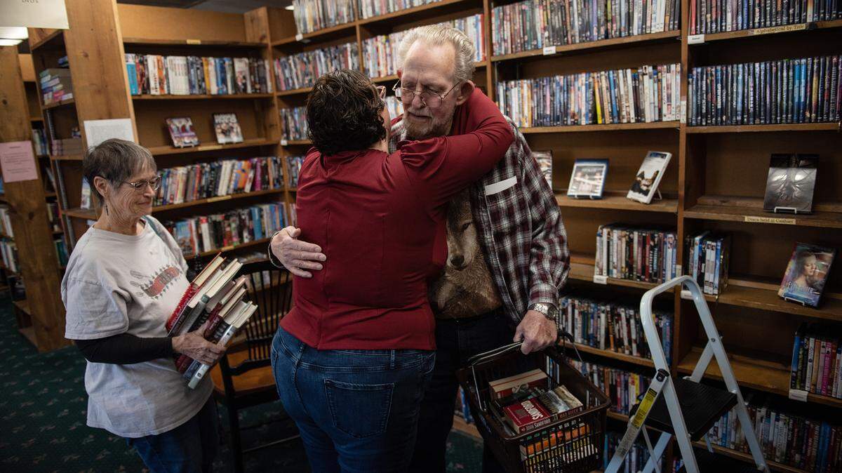 Longtime customer Don Arney gives owner Paula Kiss a hug at Yesterday’s Books in Modesto, Calif., Thursday, Oct. 27, 2022. Barbara Arney, left, picked up a stack of cookbooks during one of her last visits to the store after Kiss announced that the bookshop will be closing.