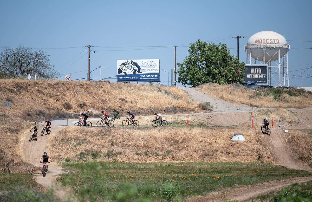 Riders in the boys JV division II race navigate the second leg of the course near the 7th Street Bridge at Tuolumne River Regional Park during the NorCal Interscholastic Cycling League event in Modesto, Calif., on Saturday, April 9, 2022.