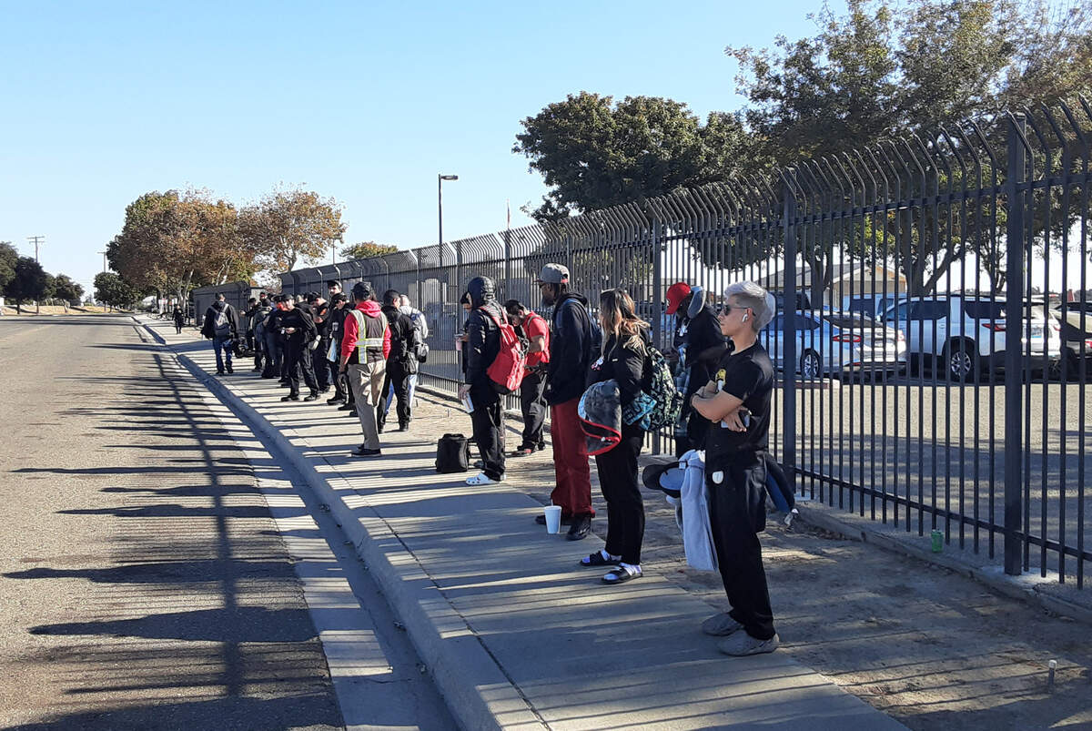 Tesla workers line up waiting for buses to take them to their Bay Area jobs in Modesto, Calif., Thursday, Oct. 27, 2022. The carmaker is leasing 500 parking spaces at the airport and will pay the city $480,000 annually.
