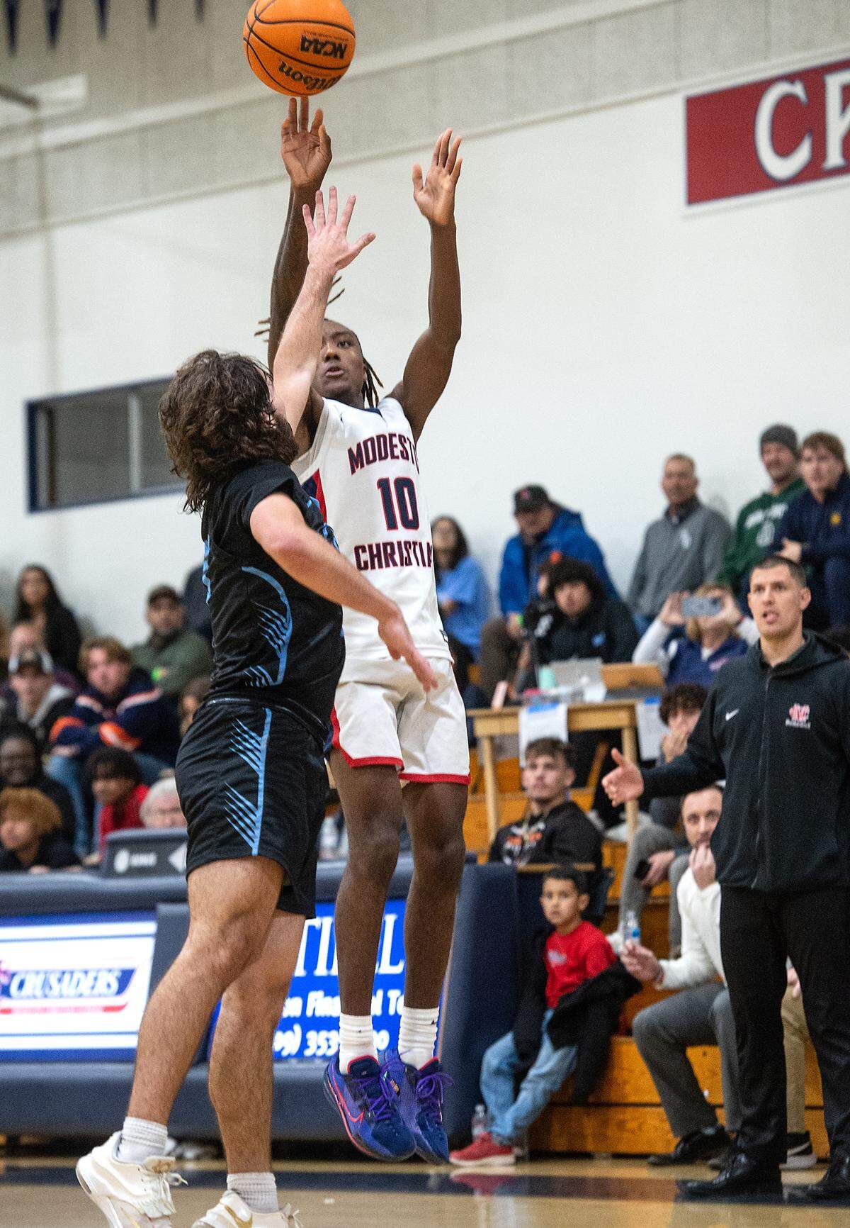 Modesto Christian’s BJ Davis lands a three point shot over Downey’s Camden Rush at the end of the fourth quarter of the first round game in the Modesto Christian Holiday Hoop Classic in Salida, Calif., Tuesday, Dec. 27, 2022.