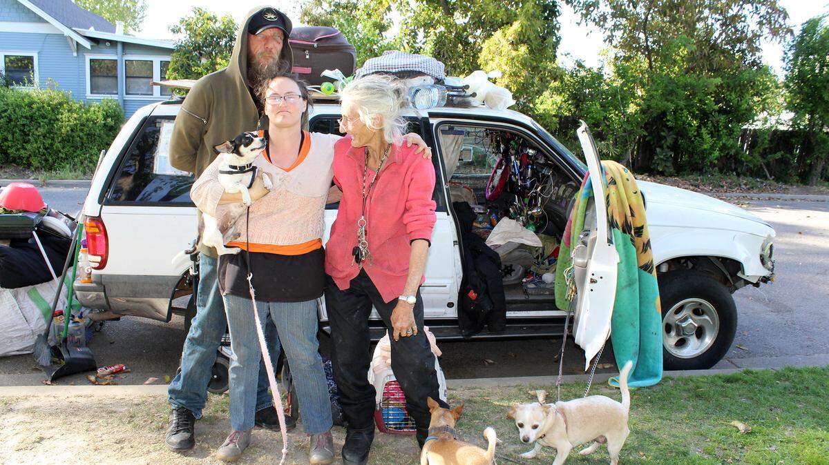 Gregory Snelson, Cathy Young, Cathy Heap and their dogs at Broadway Park in Turlock, Calif. on Tuesday, April 5, 2022. At night Heap sleeps in her car while Snelson and Young sleep on the ground next to it.