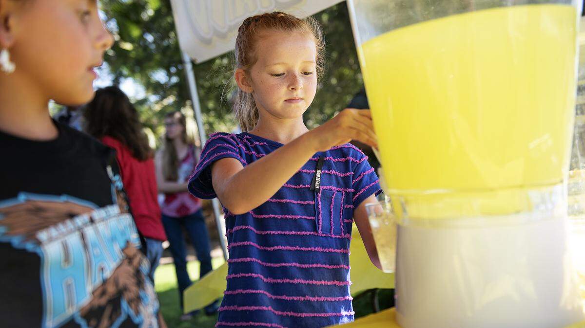 Millie Cox , 8, right, pours lemonade for people, with the help of her friend Ashlan McCurley, 9, left, at Valley Home Park in Valley Home, Calif., Friday, Aug. 16, 2019. Millie raised over a $1000 for the purchase of mourning bands law enforcement wear across their badges when a fellow officer is killed in the line of duty.