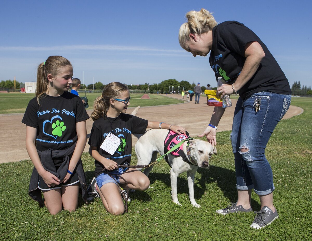 Ellie Hart middle gives some love to Poppy, her service dog, as Ellie's mom Emily Hart give praise too. Ellie Hart spearheaded a walkathon to raise money to get a service dog for her friend Peyton Bruce, left, a 10-year-old with Type 1 diabetes Sunday May 13, 2018 morning at Pitman High School