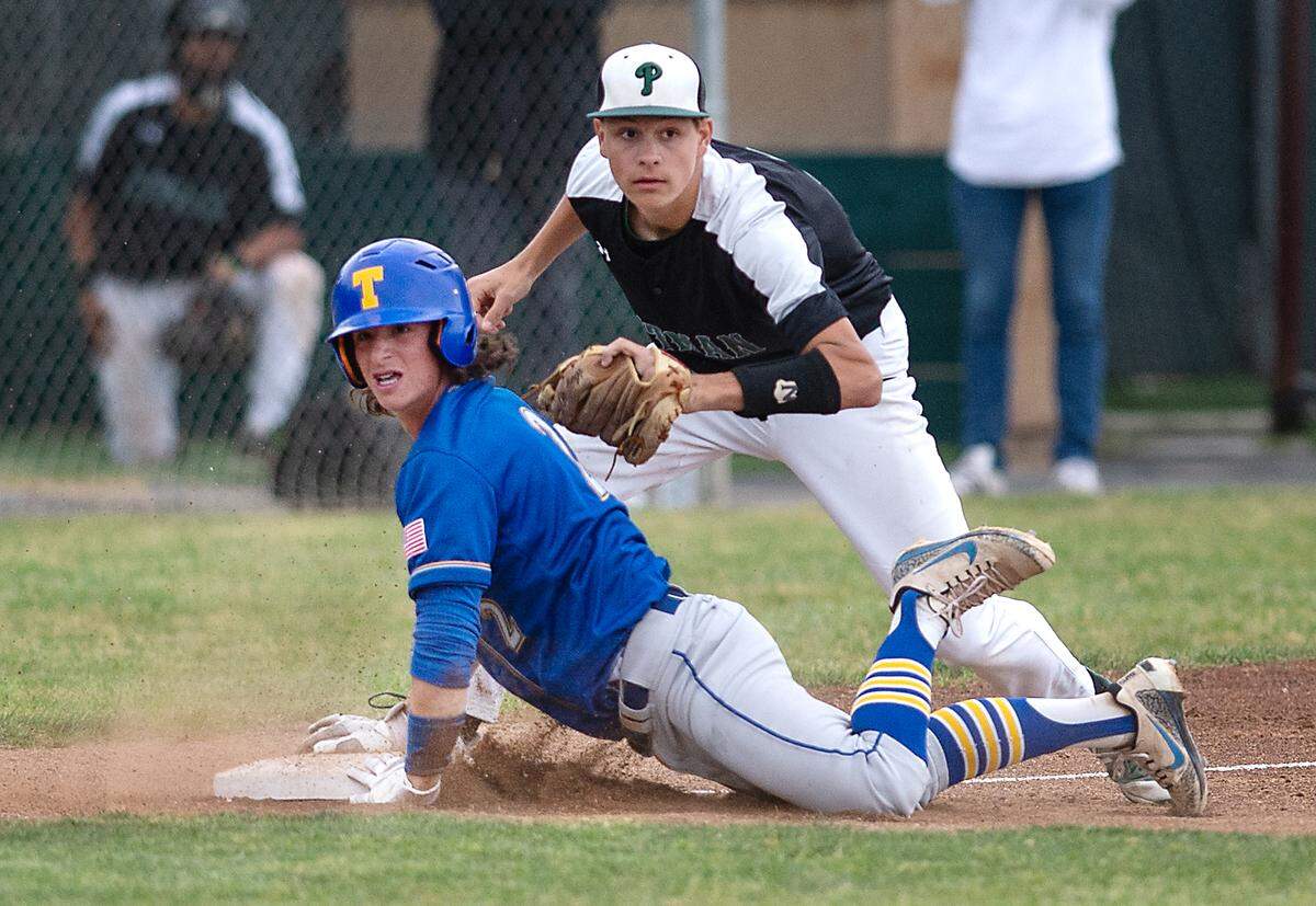 Turlock’s Gannon Evans and Pitman third baseman Karson Valenti look for the call at third the Central California Athletic League game with Pitman at Pitman High School in Turlock, Calif., on Thursday, April 14, 2022. Evans was safe and later scored on a squeeze play.