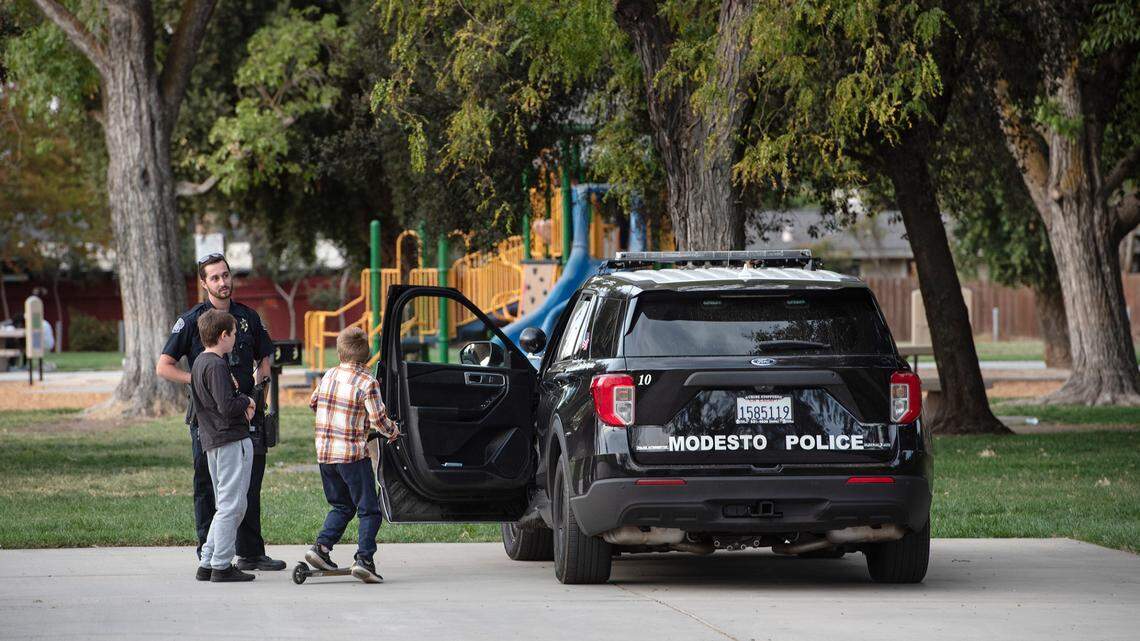 Modesto police officer Ryan Seller talks with two young boys in Roosevelt Park in Modesto, Calif., on Tuesday, Oct. 19, 2021.