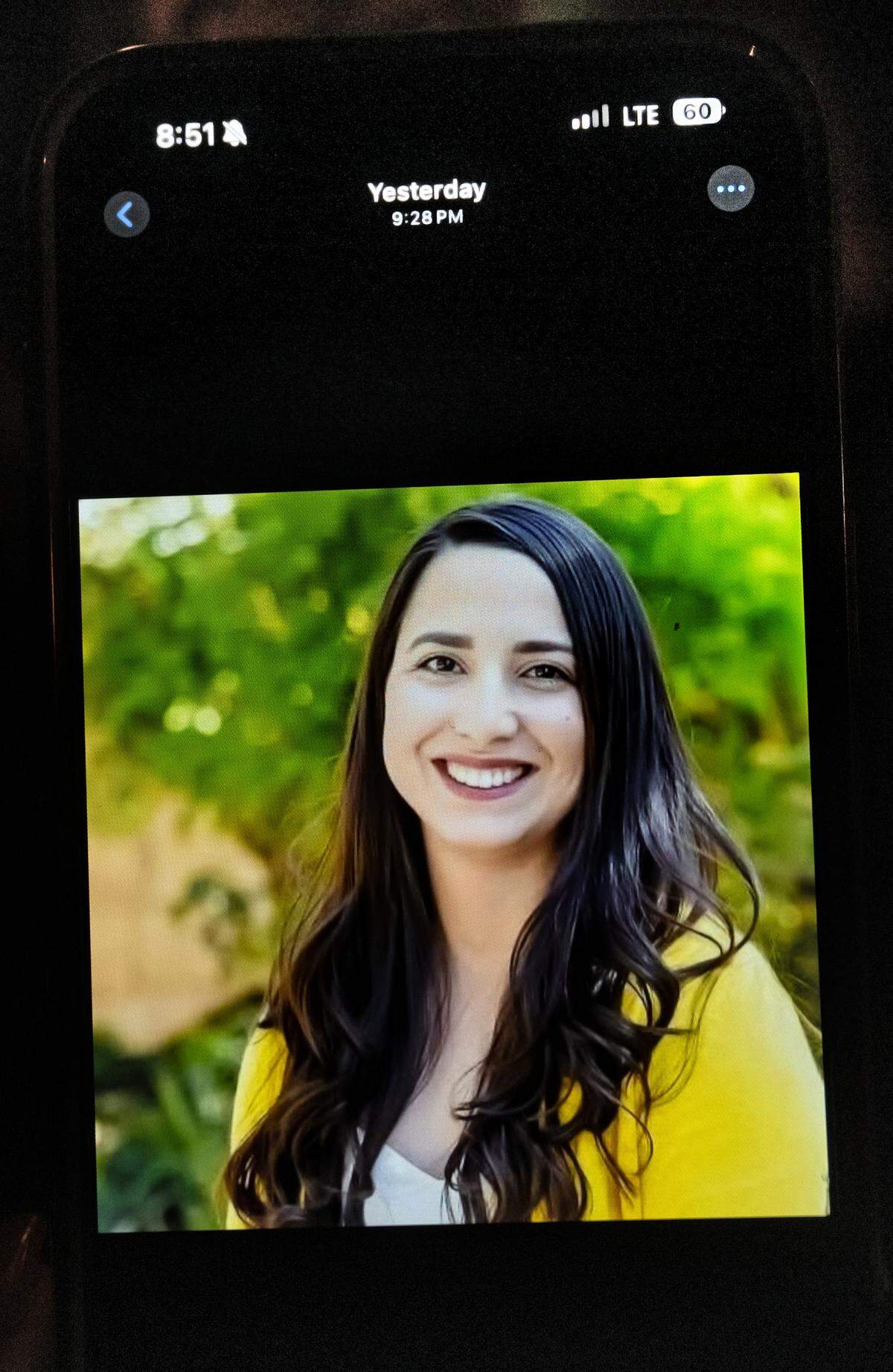 A photograph of Dinella Madrigal is seen on a phone of a friend during a candlelight ceremony in Hughson, Tuesday, May 6, 2025.