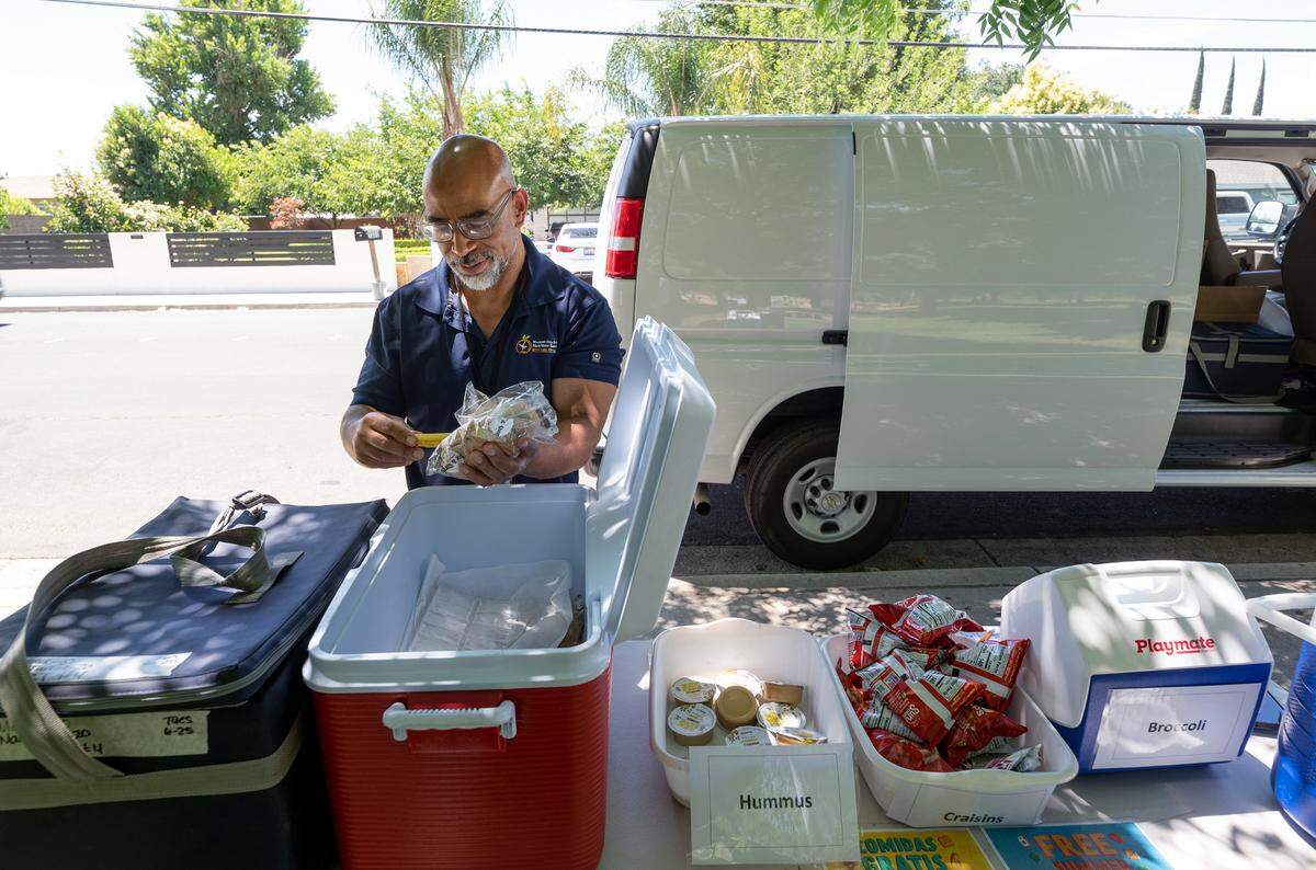 Nutrition services worker Rick Borns checks the temperature of the food before serving lunch as part of the Modesto City Schools’ summer lunch program at Mark Twain Park on California Avenue in Modesto, Calif., Tuesday, June 25, 2024.