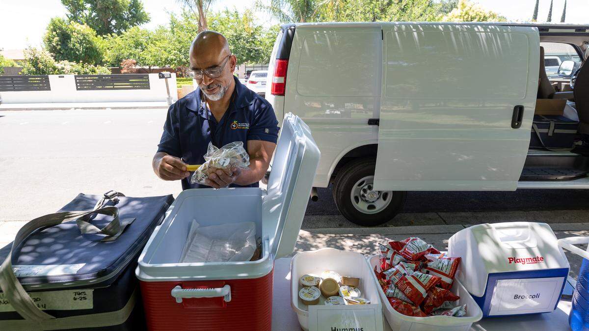 Nutrition services worker Rick Borns checks the temperature of the food before serving lunch as part of the Modesto City Schools’ summer lunch program at Mark Twain Park on California Avenue in Modesto, Calif., Tuesday, June 25, 2024.