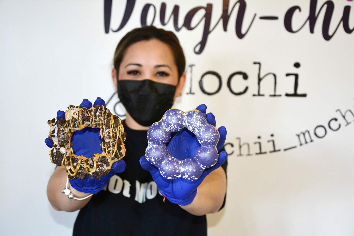 Dough-chii Mochi owner Hellen Vath holds up some of her mochi donuts in her shop in Salida, Calif. April 24, 2021.