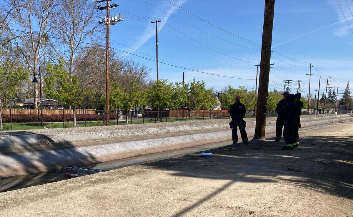 Modesto firefighters stand watch over a body found in the Root Lateral Canal, near Stoddard Avenue, around 10:30 a.m. on March 27, 2023.