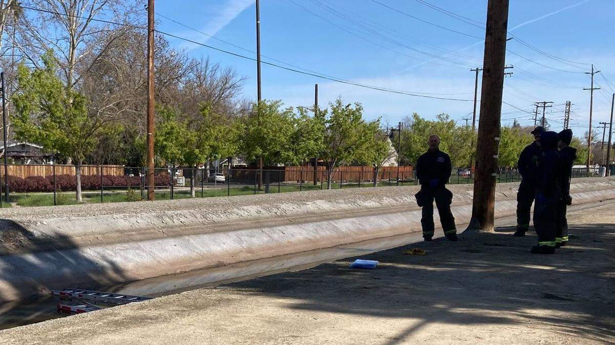 Modesto firefighters stand watch over a body found in the Root Lateral Canal and Stoddard Avenue, around 10:30 a.m. on March 27, 2023.