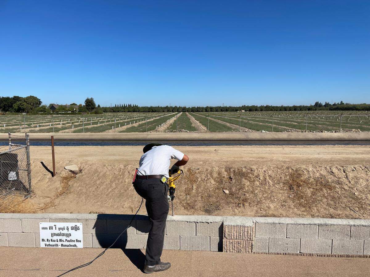 Ry Kea drills a hole into the concrete wall surrounding the Modesto Cambodian Buddhist Society temple complex. He is installing razor wire around parts of the perimeter.