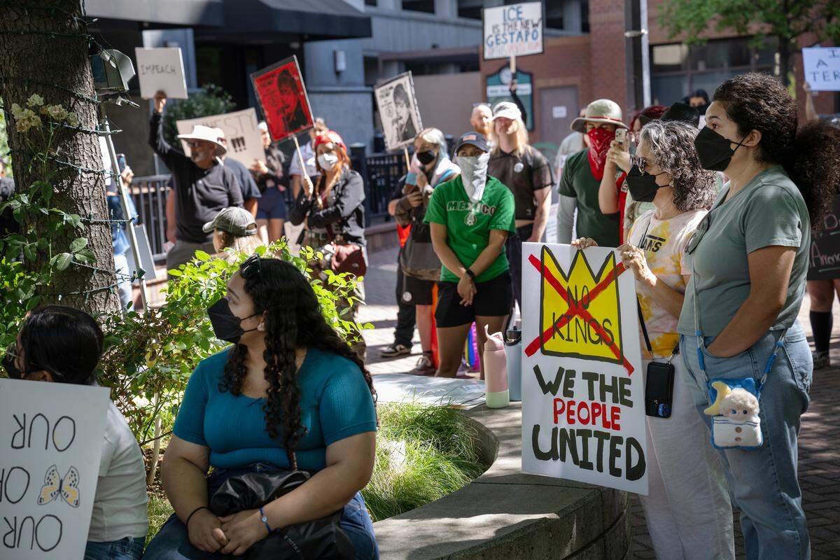 A group listens to speakers as protestors gathered at 10th Street Place to oppose Trump Administration policies in Modesto, Saturday, June 14, 2025.