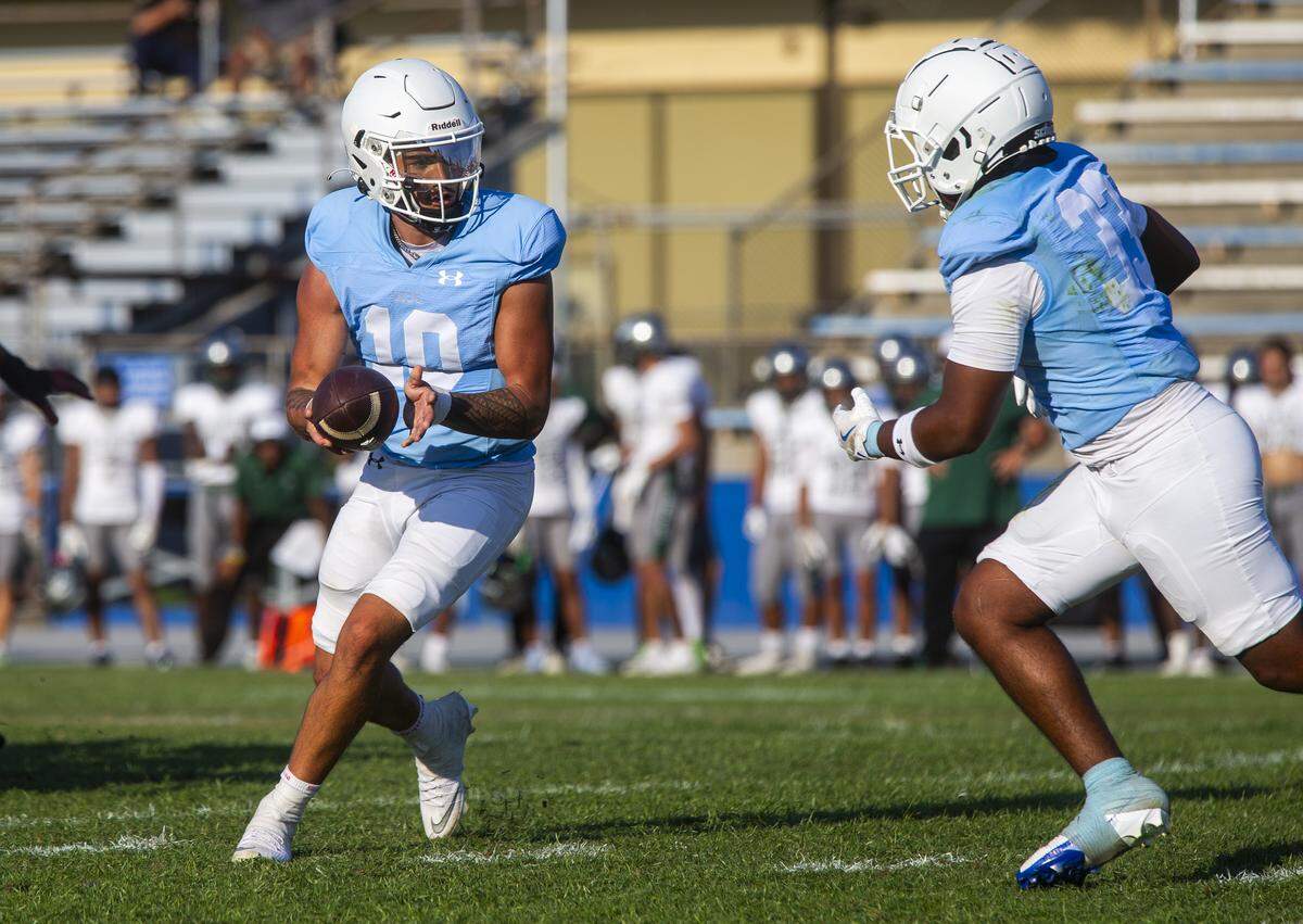 DayDay Tafoya, 10, hands the ball to Aiden Muhammad, 33, during the first half of a nonconference game against Laney College at Modesto Junior College on Saturday, Aug. 30, 2025.