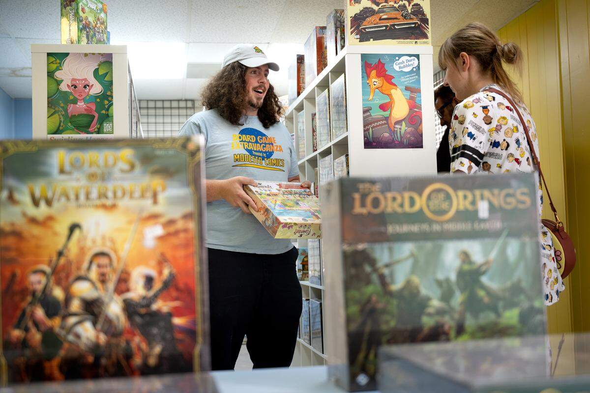 Rob Van Tuinen shows Heather Harless the game Flamecraft at Meeple Valley Board Game Cafe in Modesto on March 21, 2024. 