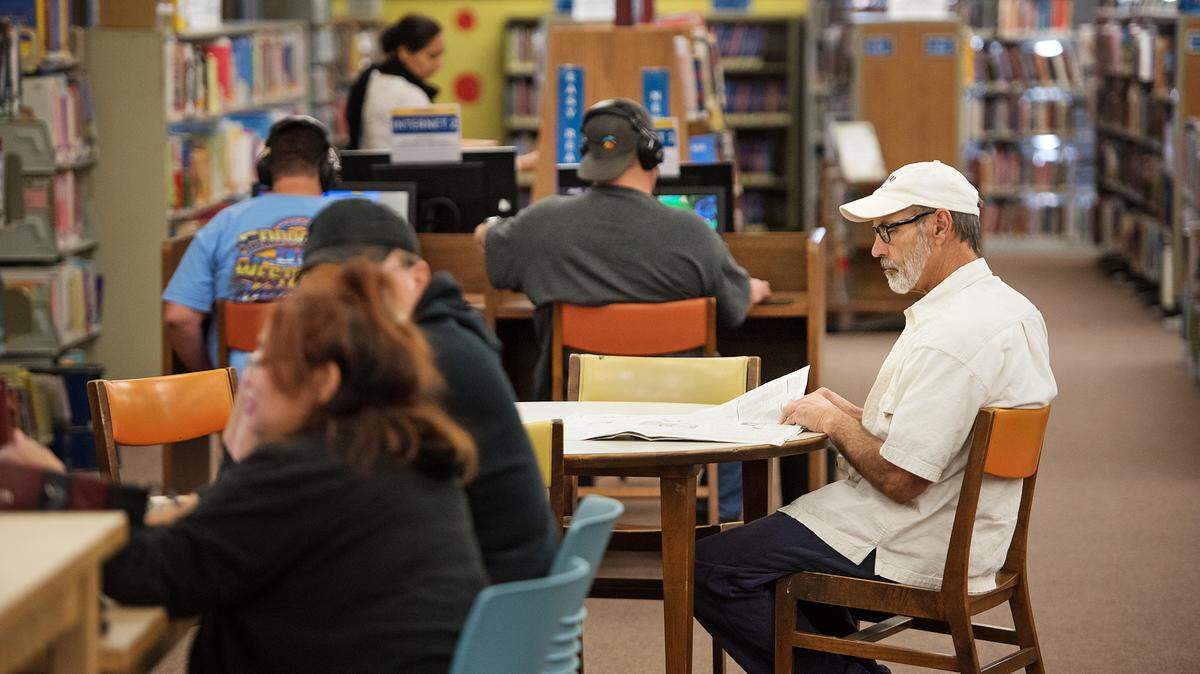 Turlock resident David Cone, right, reads the newspaper at as other use library service at the Stanislaus County Library in Turlock, Calif., on Thursday, Oct. 11, 2018.
