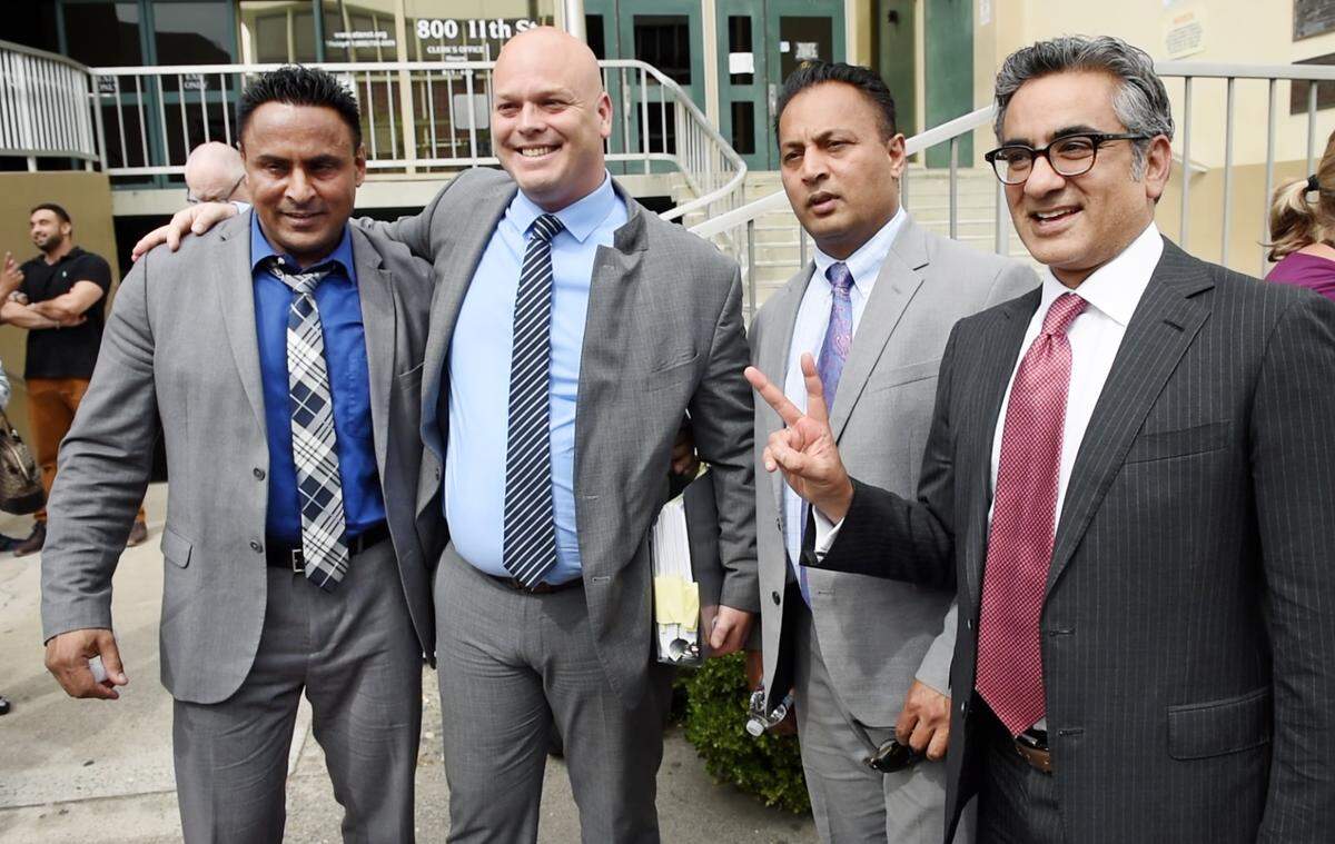 Brothers Daljit Atwal, left, and Baljit Athwal, second from right, pose for pictures with their lawyers, Hans Hjertonsson and Jai Gohel, right, outside Stanislaus County Superior Courthouse after a jury found them not guilty of murder in Modesto, Calif., Friday, June 30, 2019. The brothers spent the past four years accused of murder in the death of Korey Kauffman.