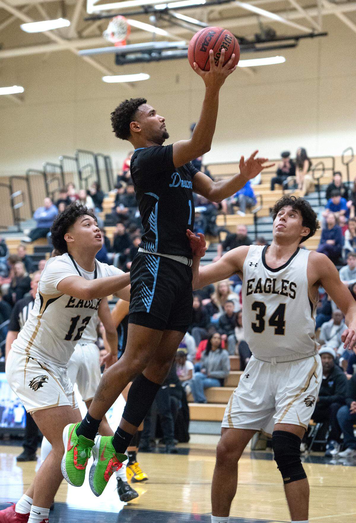 Downey’s Jorden Lewis scores on a layup past Enochs defenders Troy Navarro (12) and Emiliano Arreola (34) during the Central California Athletic League game at Enochs High School in Modesto, Calif., Friday, Jan. 27, 2023.
