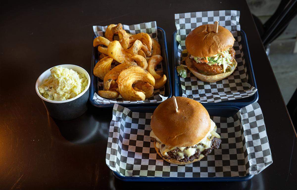 Clockwise from the bottom, baconnaise burger, potato salad, sidewinder fries, and hot honey chicken sandwich at Kinfolks Flatstone Grill in Riverbank, Friday, April 3, 2026. 