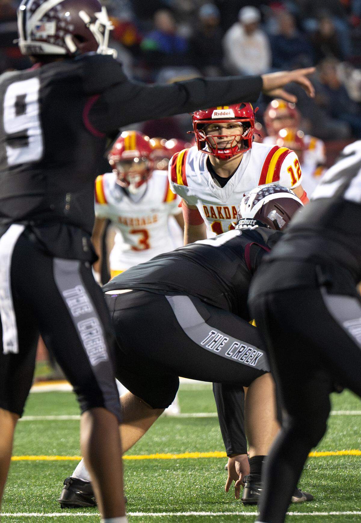 Oakdale’s Wes Burford is set on defense as Woodcreek quarterback Josiah Melendez (9) directs his players during the Sac-Joaquin Section Division III title game at Hughes Stadium in Sacramento, Friday, Nov. 28, 2025.