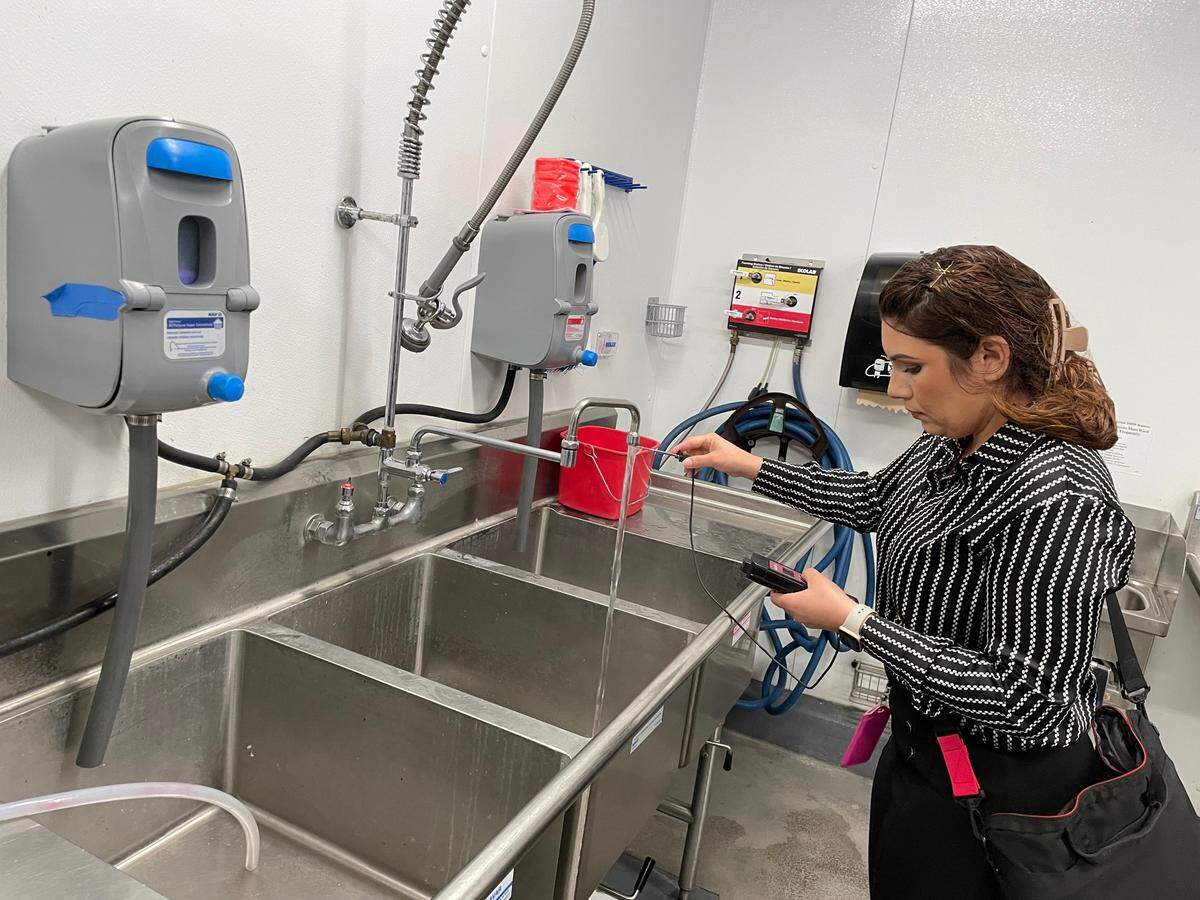 Registered Environmental Health Specialist Alondra Estrada checks the temperature of the water used for cleaning at The Tipping Point restaurant inside Save Mart on Sept. 5, 2024.