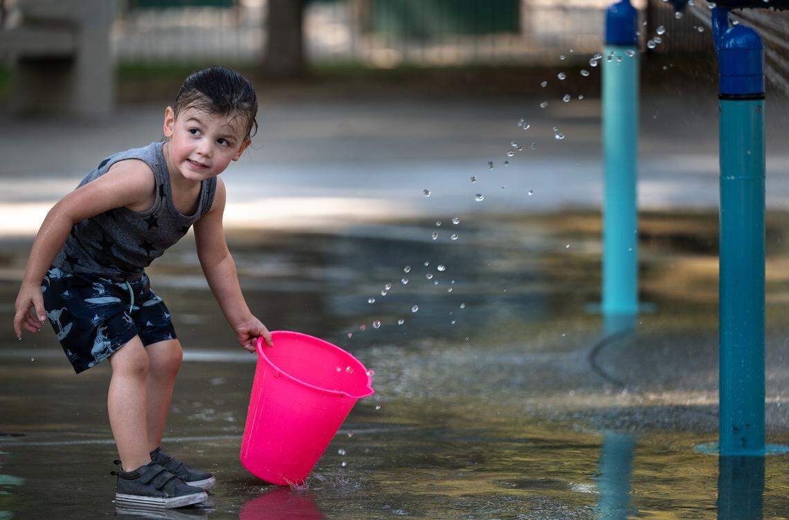 Nicholas Yarber, 3, fills a bucket as he plays in the water feature at Graceada Park in Modesto, Calif., on Friday, September 9, 2022.