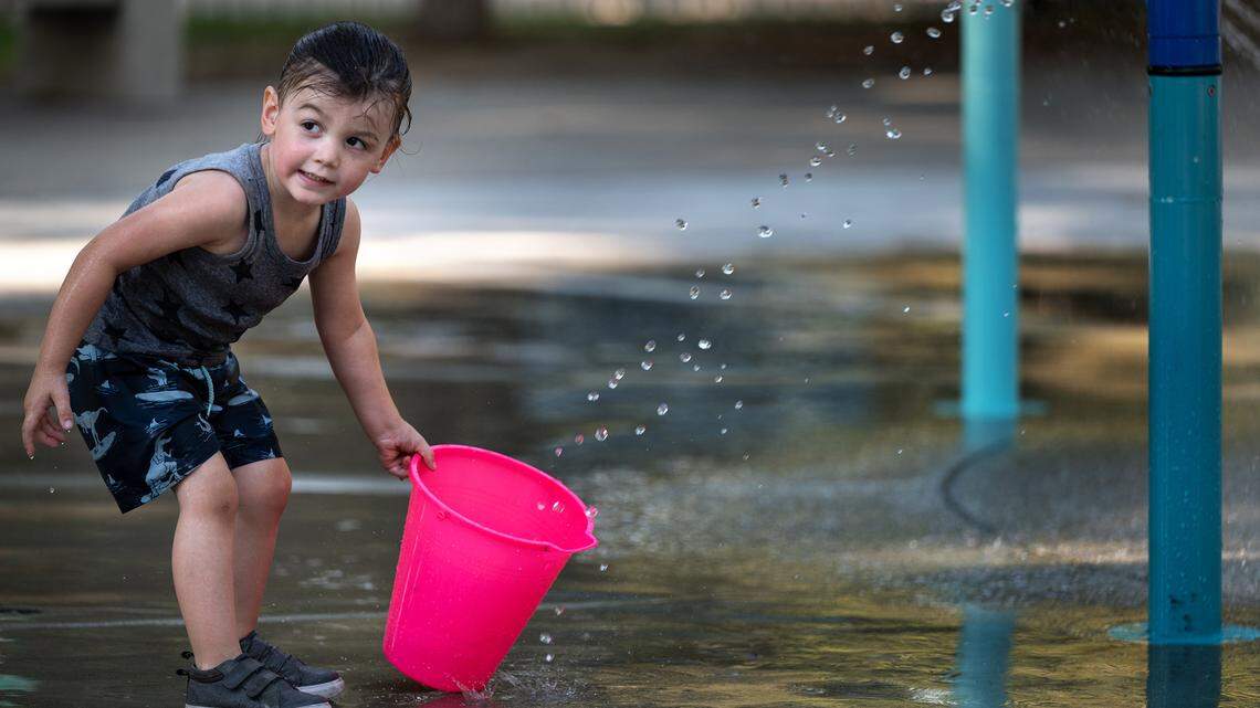 Nicholas Yarber, 3, fills a bucket as he plays in the water feature at Graceada Park in Modesto, Calif., on Friday, September 9, 2022.