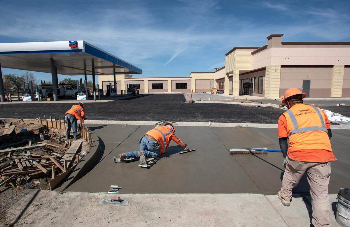 Workers finish concrete at a new Chevron gas station on Dale Road in Modesto, Calif., on Thursday, March 24, 2022.
