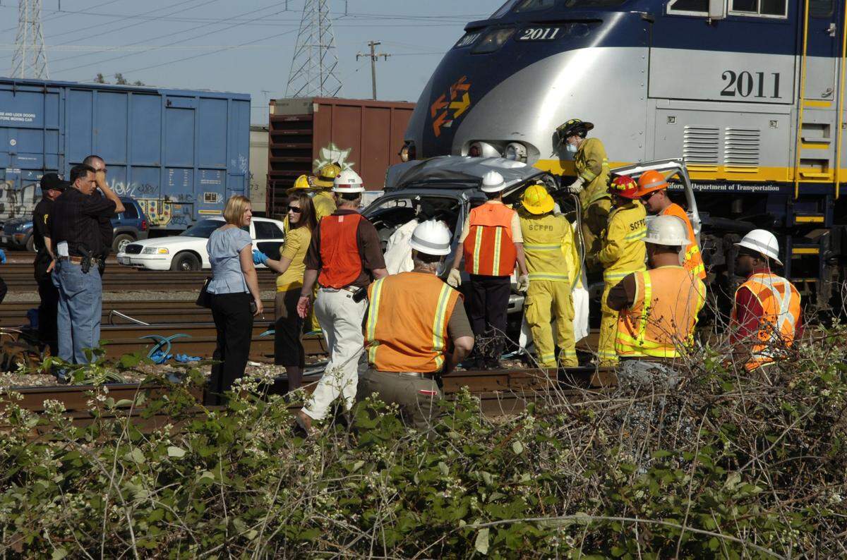 EMS, BNSF, lawenforcement personel and the coroners office gather around the front of an Amtrak passenger train in Riverbank after it collided with an SUV, killing 5-6 people. Fire dept personel were using the “jaws of life” to pry the vehicle off the front of the train. The north bound train collided with the SUV that was traveling east bound on Claribel Road. The SUV was literally wrapped around the front of the train. The train came to a stop, approximately 500 yard north of the incident. Tuesday, May 8, 2007 in Modesto Califoria. Modesto Bee/ Bart Ah You