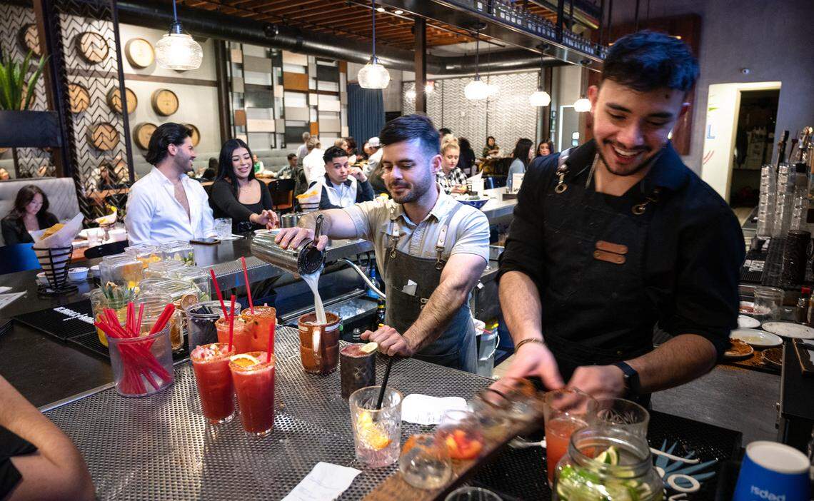 Bartenders Luis Torres, middle, and Frankie Ramirez, right, prepare drinks at Memo’s Cocina & Tequila Bar in Turlock, Calif., Friday, Jan. 20, 2023.