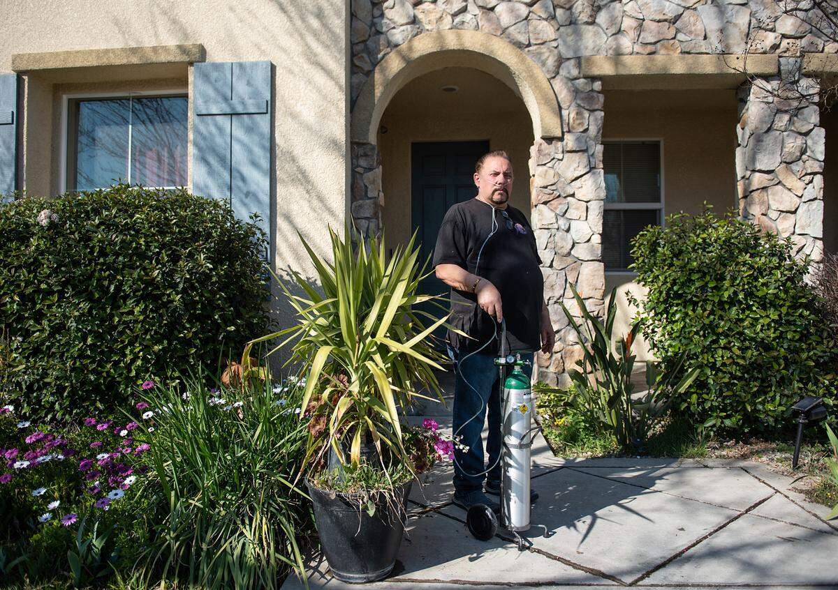 Mickey Davis outside his home in Modesto, Calif., on Friday, Feb. 25, 2022. Davis, 64, came down with COVID pneumonia and was hospitalized for 17 days starting in September 2021. Five months later, he still has breathing problems and uses oxygen at home.