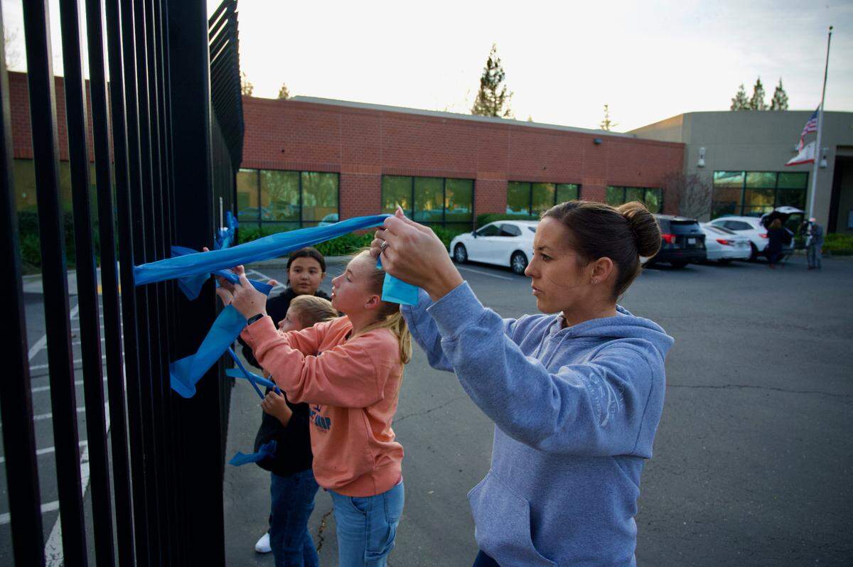 Christi Drake and family members tie blue ribbons outside Elk Grove city buildings and the police department on Friday, Jan. 21, 2022, in honor of Elk Grove Police Officer Tyler Lenehan, killed after being struck by a wrong-way driver on Highway 99 that morning. “My husband works for a different department, but we’ve done this for quite a few Northern California law enforcement officers that have passed away on and off duty,” she said. “It hits close to home.”