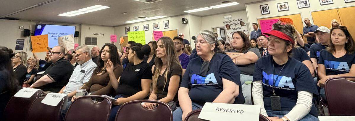 MTA teachers held up their signs as members spoke during public comment about why they are requesting an increase of healthcare contribution from the district.