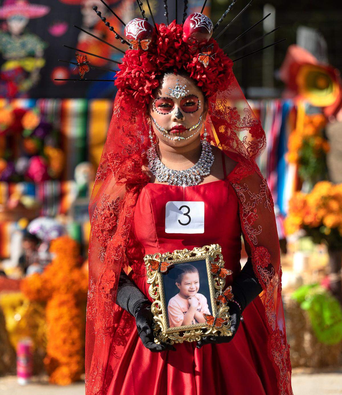 Yosephineh Vilchiz, 11, holds a picture to remember her cousin Tony Salazar, 8, who died last year of leukemia. Yosephineh dressed as a traditional Catrina for the Dia de los Muertos celebration at Fairview Park in Modesto, Calif., Saturday, Oct. 29, 2022. She placed first in the Catrina contest.
