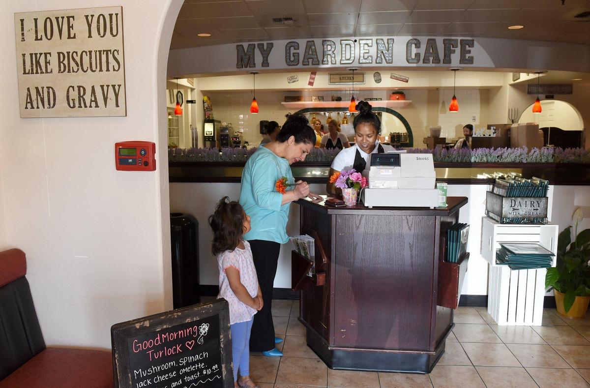 Sovanna Soun rings up customer Shamreta Ibrahim as her daughter Emily 4yrs stands by at My Garden Cafe in Turlock, Calif. on Saturday morning May 25, 2019.