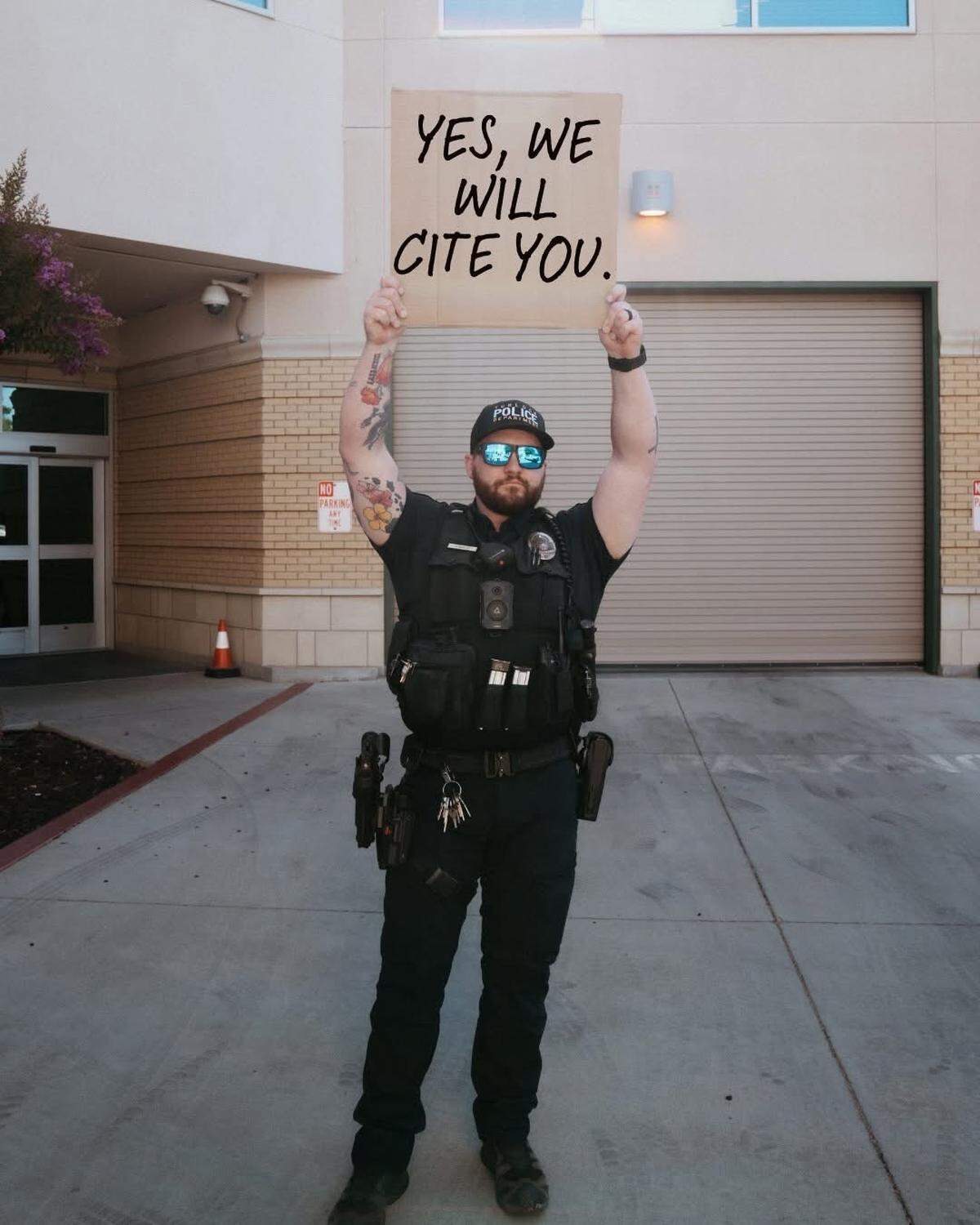 A Turlock police officer holds a sign warning residents that citations will be issued for illegal fireworks use.