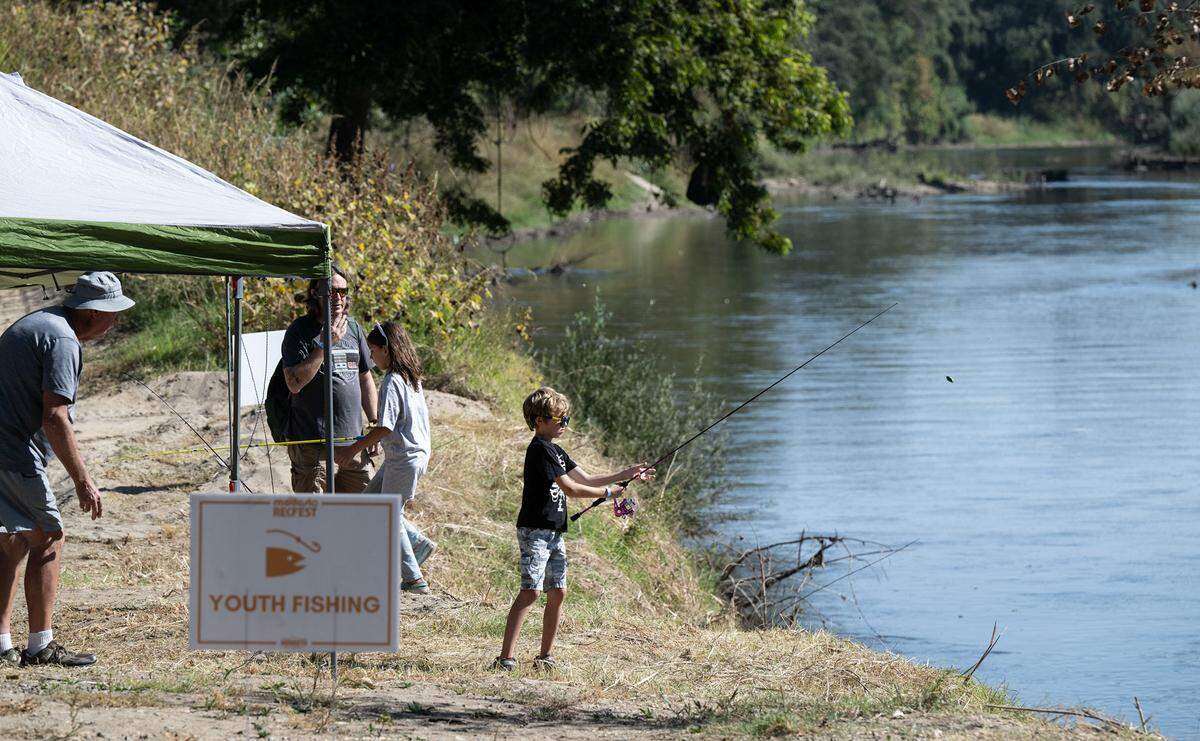 Carson Lien, 9, middle, casts with a fishing pole at the youth fishing station on the Tuolumne River during Modesto RecFest at Gateway Park in Modesto on Oct. 21, 2023.
