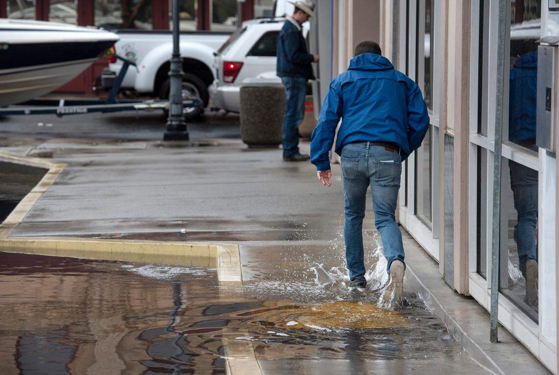 A man passes through a flooded parking lot in Oakdale, Calif., on Monday, Dec. 27, 2021.