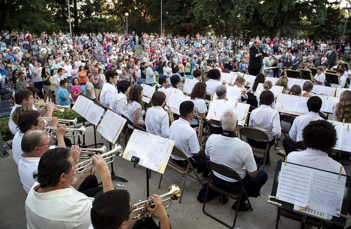 People stand as the band plays the National Anthem during the pening night concert of MoBand at the Mancini Bowl in Modesto’s Graceada Park on Thursday, June 9, 2016.