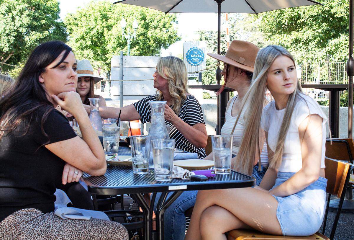 Heather Kroll (left) and Abbie Kroll (right) watch businesses set up outdoor street dining tables while eating in Turlock, Calif. on July 23, 2020.