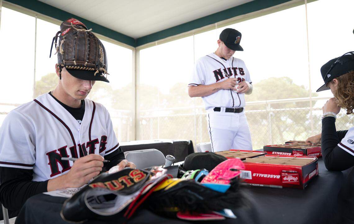 Modesto Nuts players including Matt Tiberia, left, sign baseballs during Modesto Nuts media day at John Thurman Field in Modesto, Tuesday, April 1, 2025.