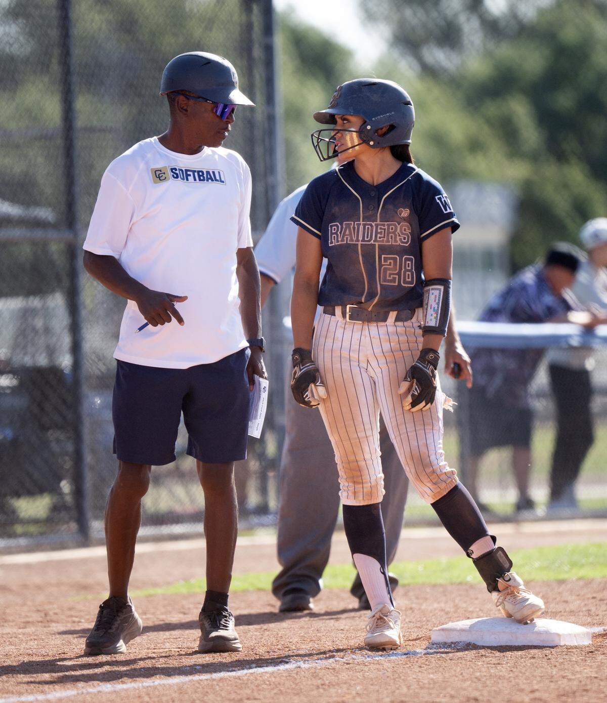 Central Catholic head coach Sam Nichols talks with Taryn Calderon at third base during the Sac-Joaquin Section Division 3 semifinal playoff game with Manteca at Central Catholic high School in Modesto, Wednesday, May 20, 2025.