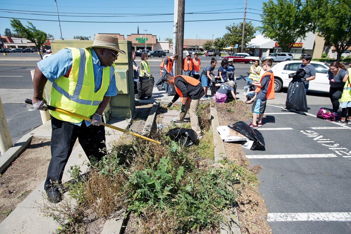 Jeremiah Williams, left, and other volunteers clean up McHenry Avenue during Love Modesto, a community-wide volunteer day, in Modesto, Calif., on Saturday, April 21, 2018.
